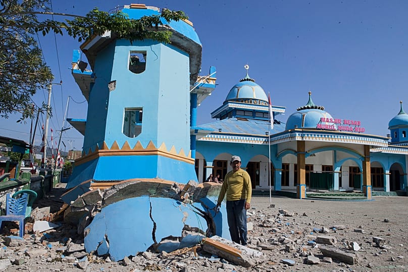 A man stands next to the tower of a mosque that collapsed during an earthquake in Reo, 17 August, 2026