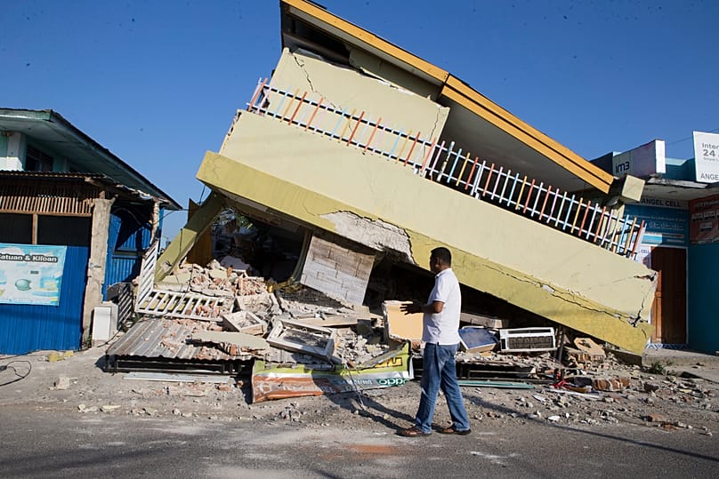 A man walks building collapsed during an earthquake in Reo, 17 August, 2026