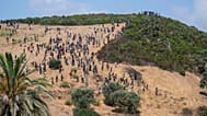 Migrants gather on a hill as they attempt crossing from the border town of Fnideq to the Spanish enclave of Ceuta, Saturday, Aug. 15, 2026. 