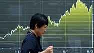 Eine Person läuft vor einer elektronischen Kurstafel, die den japanischen Nikkei-Index zeigt, bei einem Wertpapierhaus in Tokio, 13. August 2026.