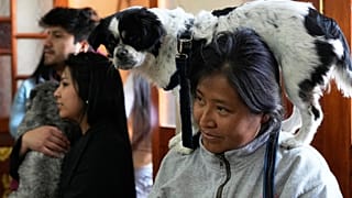 A woman carrying her dog on her shoulders attends Mass at the Gran Poder parish marking the feast day of San Roque, the patron saint of dogs, in La Paz, Bolivia, Sunday, Aug. 