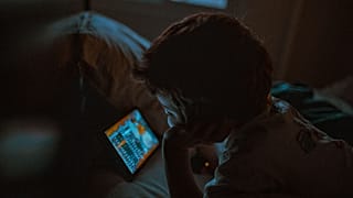 A young child watching a tablet at night.