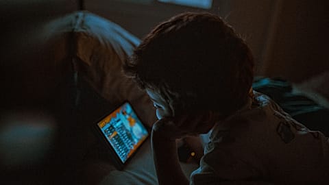 A young child watching a tablet at night.