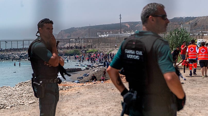 Spanish Guardia Civil officers stand guard as migrants cross from Morocco into the Spanish enclave of Ceuta, Thursday, July 30, 2026