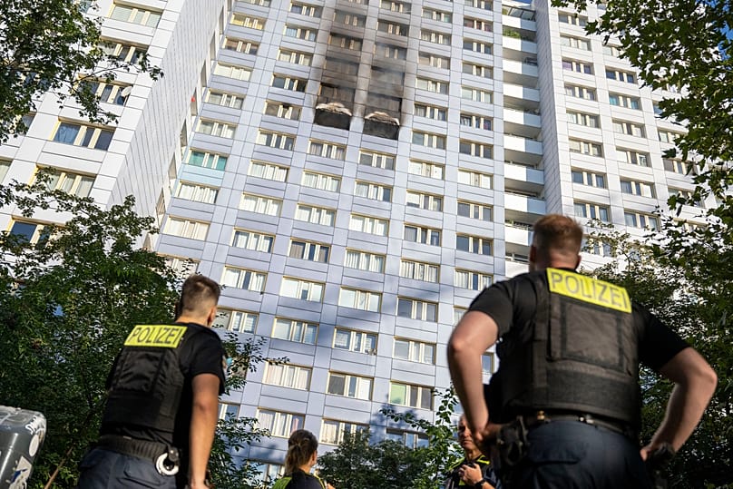 Feuerwehrleute blicken auf das Hochhaus in Berlin-Friedrichshain