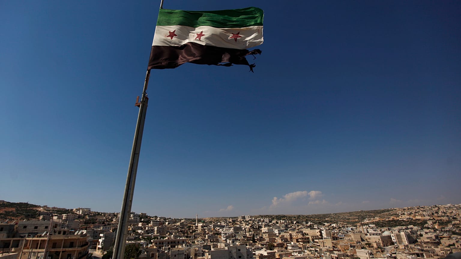 علم ثوري سوري يلوح فوق مبنى على مشارف حلب، سوريا، الثلاثاء 12 يونيو 2012. 