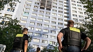 Police officers stand in front of a high-rise building after a fire in Friedrichshain, 14 August, 2026