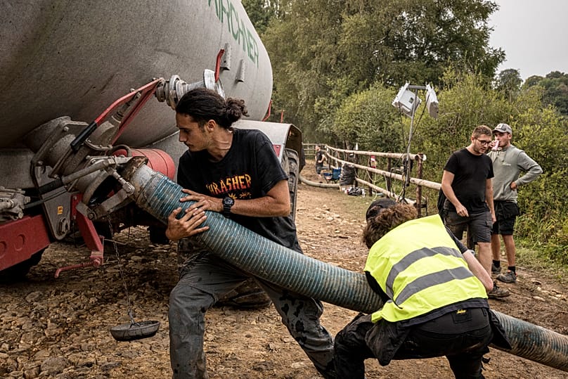 Αγρότες γεμίζουν με νερό τα ρυμουλκούμενα των τρακτέρ τους σε τοπική λίμνη, καθώς συμμετέχουν στην κατάσβεση δασικής πυρκαγιάς που καίει κοντά στο Sourbrodt, 17 Αυγούστου 2026
