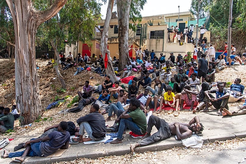 Unos migrantes descansan frente al Centro de Acogida Temporal de Inmigrantes (CETI) tras cruzar desde Marruecos al enclave español de Ceuta, el viernes 31 de julio de 2026. 