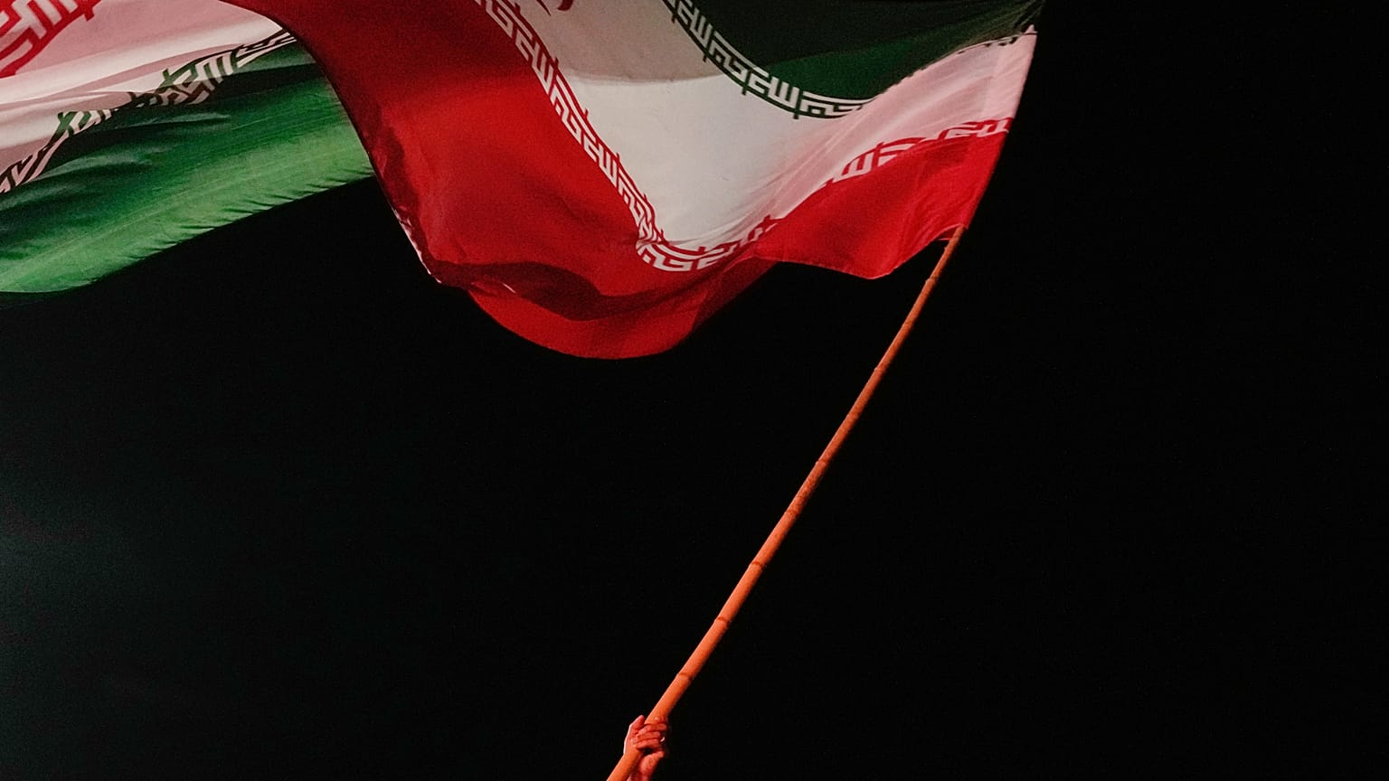 رجل يلوح بالعلم الإيراني خلال تجمع موالي للحكومة في ساحة بطهران، إيران، الثلاثاء 11 أغسطس 2026. (AP Photo/فاهد سليمي)