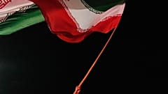 رجل يلوح بالعلم الإيراني خلال تجمع موالي للحكومة في ساحة بطهران، إيران، الثلاثاء 11 أغسطس 2026. (AP Photo/فاهد سليمي)