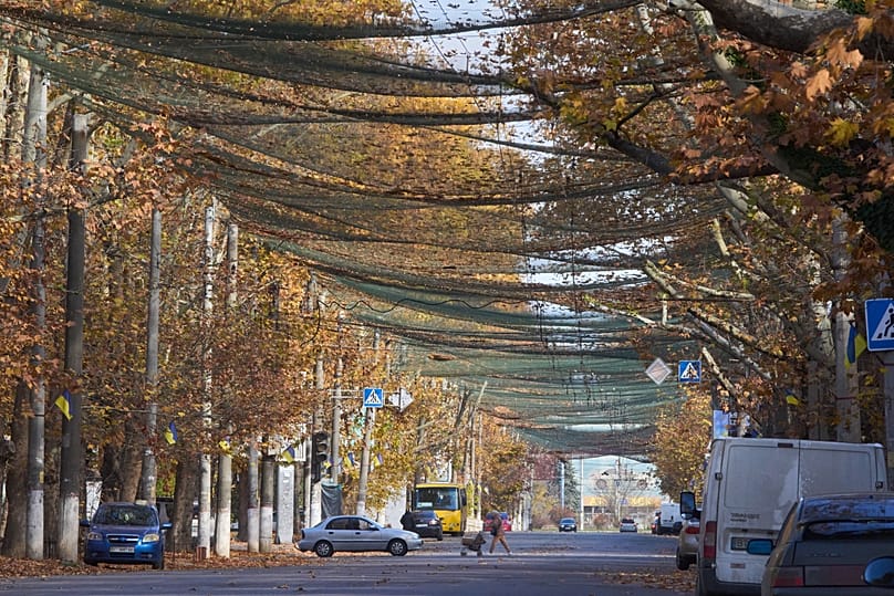 Local residents go along the street covered with an anti-FPV-drone net in the frontline city of Kherson, 3 November, 2025