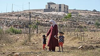 رقية، زوجة المالك الفلسطيني الأمريكي المقيم في ولاية أوهايو لوي ريدي، تمشي مع ابنتيهما كيندا، 2، على اليسار، وحور، 4، في منزلهما الذي حاصره المستوطنون الإسرائيليون 