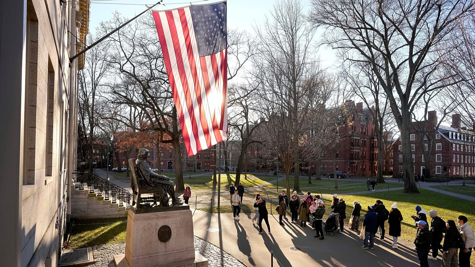  People take photos near a John Harvard statue, left, on the Harvard University campus, 2 Jan., 2024, in Cambridge, Mass. (AP Photo/Steven Senne, File)