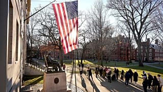  People take photos near a John Harvard statue, left, on the Harvard University campus, 2 Jan., 2024, in Cambridge, Mass. (AP Photo/Steven Senne, File)