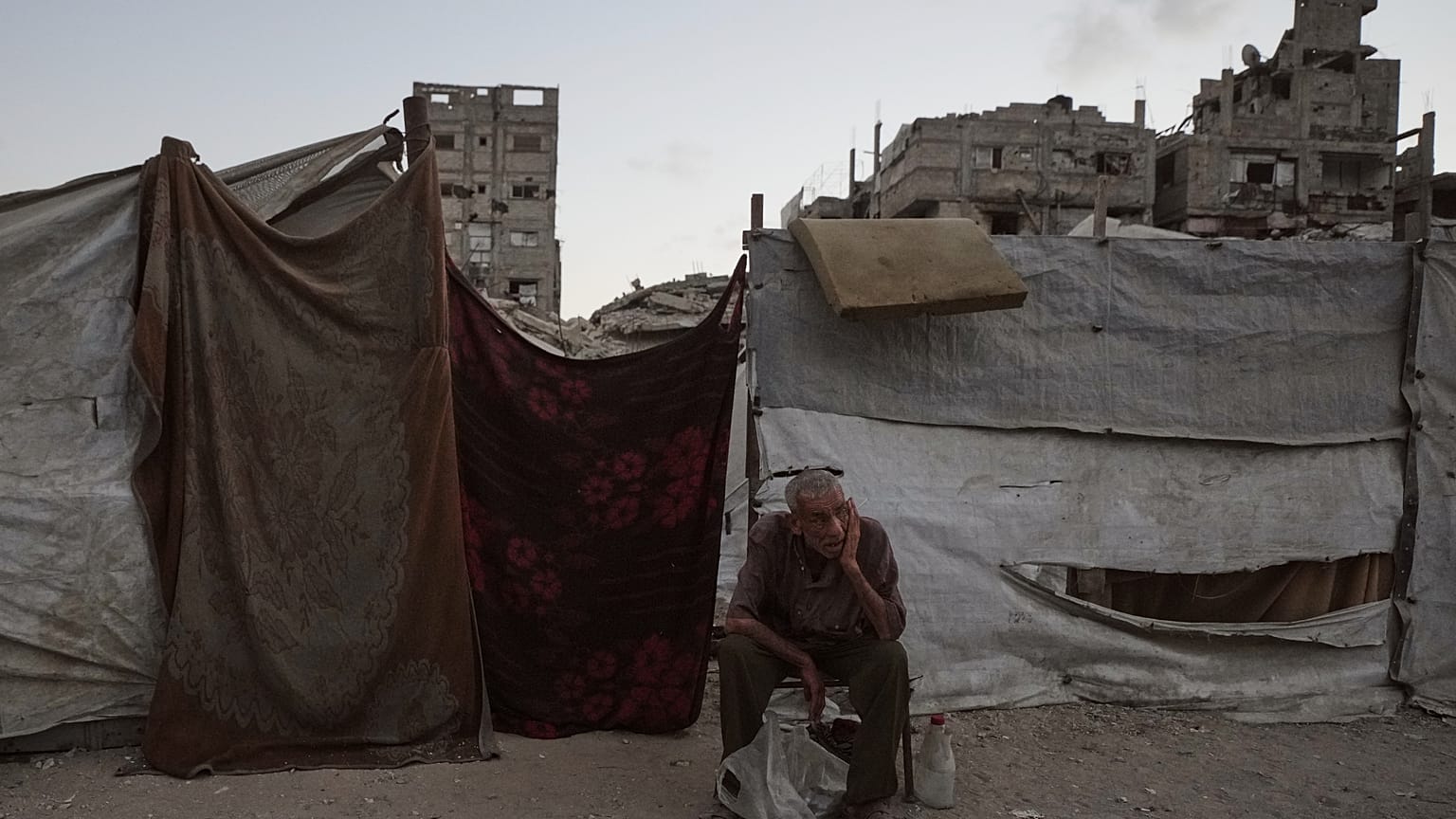 رجل فلسطيني يجلس بجوار خيمته، حيث يحتمي وسط أنقاض المباني التي دمرتها الغارات الجوية الإسرائيلية خلال الحرب مع حماس، في مدينة غزة، الاثنين 17 أغسطس/آب 2026.