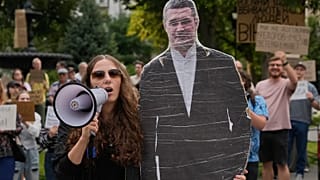 Ludzie skandują przy kartonowej podobiznie Mychajła Fedorowa podczas protestu przeciw jego odwołaniu z funkcji ministra obrony Ukrainy w Kijowie, 14 sierpnia 2026 r.