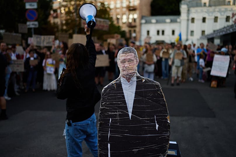People shout slogans next to a cardboard cutout photo of Mykhailo Fedorov during a rally to protest his dismissal as Ukraine's Defense Minister in Kyiv, Friday, Aug. 14, 2026.