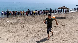 ARCHIVO: Un migrante huye de agentes que acordonan el acceso a la playa para impedir el paso a las personas que cruzan desde Marruecos, el 31 de julio de 2026.