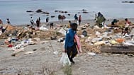 Varios inmigrantes que cruzaron de Marruecos a España recogen sus pertenencias tras ser desalojados de una playa en Ceuta, el jueves 20 de agosto de 2026