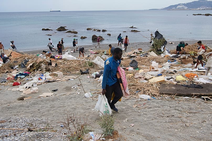 Migrants who crossed from Morocco into Spain gather their belongings after being cleared from the beach in Ceuta, 20 August, 2026