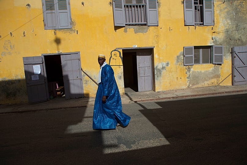 A man walks past a colonial era building in Saint-Louis, Senegal, Saturday, May 18, 2013.