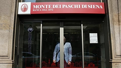 A man waits for the sliding doors to open so he can leave a Monte dei Paschi di Siena branch in Milan, Italy, on 5 July 2017. (AP Photo/Luca Bruno, file)