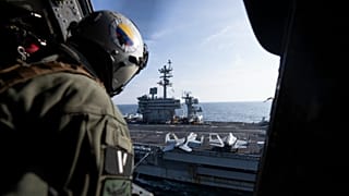 A Naval Air crewman looks at the aircraft carrier USS George Washington off the coast of Argentina, 30 May, 2024