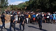 Migrantes que passaram de Marrocos para Espanha são escoltados pela polícia espanhola para abrigos temporários após serem retirados de uma praia em Ceuta, enclave espanhol