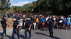 Migrantów, którzy przedostali się z Maroka do Hiszpanii, hiszpańska policja eskortuje do tymczasowych schronień po usunięciu ich z plaży w Ceucie