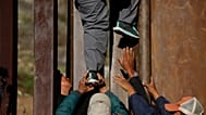 ARCHIVO - Migrantes hondureños se ayudan mutuamente a cruzar el muro fronterizo de EE.UU. hacia San Diego, California, desde Playas en Tijuana, México, el miércoles 12 de 2018