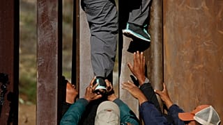 ARCHIVO - Migrantes hondureños se ayudan mutuamente a cruzar el muro fronterizo de EE.UU. hacia San Diego, California, desde Playas en Tijuana, México, el miércoles 12 de 2018