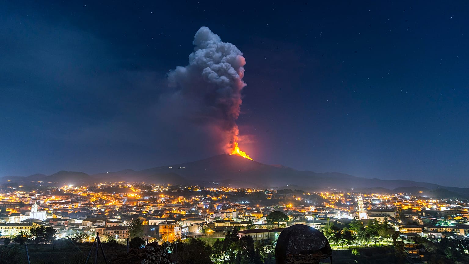 Llamas y humo que se elevan desde un cráter, vistos desde la ladera sur del Etna, se alzan sobre la ciudad de Pedara, en Sicilia, la noche del 24 de febrero de 2021.
