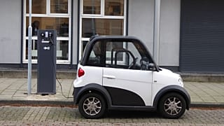 A compact black and white electric car at a charging station