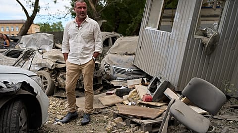 American actor Liev Schreiber stands next to destroyed cars during his trip for Ukraine's Independence day as UNITED24 ambassador in Kyiv, Ukraine, Thursday, Aug. 20, 2026. 