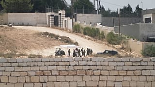 مستوطنون إسرائيليون يقومون بدوريات على طريق أمام منازل فلسطينية محاصرة، في قرية قصرة المحتلة بالضفة الغربية، جنوب نابلس