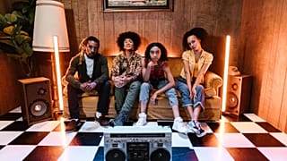 Four young people sitting in a retro-themed room. 