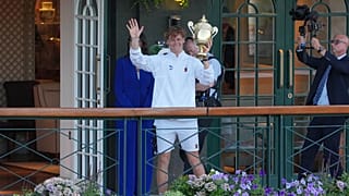 Jannik Sinner présente son trophée au public devant le Centre Court après avoir remporté la finale du simple messieurs de Wimbledon, à Londres, dimanche 12 juillet 2026.