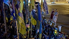 Women pray before a memorial of Ukrainian flags and photographs displayed in memory of civilians and soldiers killed during the war with Russia in central Kyiv, Friday.