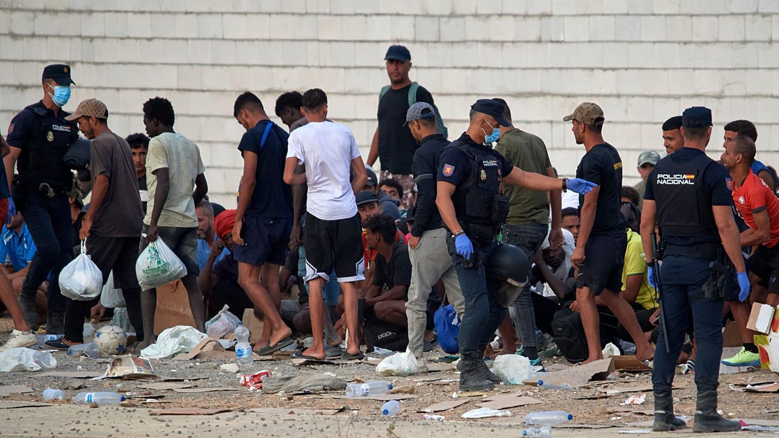 Migrantes que cruzaron de Marruecos a España hacen fila para recibir alimentos en una playa del enclave español de Ceuta, España, el 19 de agosto de 2026.