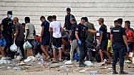 Migrantes que cruzaron de Marruecos a España hacen fila para recibir alimentos en una playa del enclave español de Ceuta, España, el 19 de agosto de 2026.
