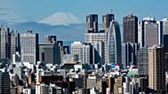 In this March 29, 2021, file photo, Mount Fuji appears behind the skyline of skyscrapers in the Shinjuku shopping and business district in Tokyo.