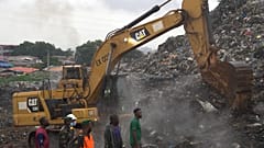 Rescue workers search through a heap of refuse after it collapsed at Conakry’s largest landfill, Guinea, Sunday, Aug. 23, 2026.