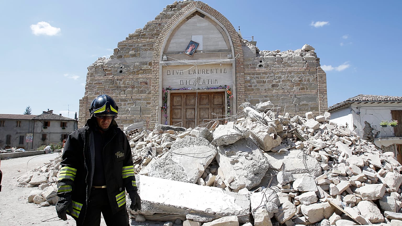 Un vigile del fuoco passa accanto ai resti di una chiesa a Villa San Lorenzo, vicino ad Amatrice, nell'Italia centrale, sabato 27 agosto 2016.