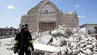 Un vigile del fuoco passa accanto ai resti di una chiesa a Villa San Lorenzo, vicino ad Amatrice, nell'Italia centrale, sabato 27 agosto 2016.