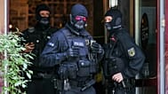 Police vehicles and officers stand during searches in the Connewitz district of Leipzig, 26 January, 2022