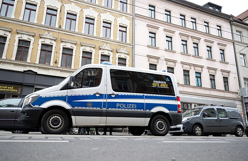 Police officers stand near to a police vehicle in front of a house in Leipzig Connewitz, 24 April, 2024