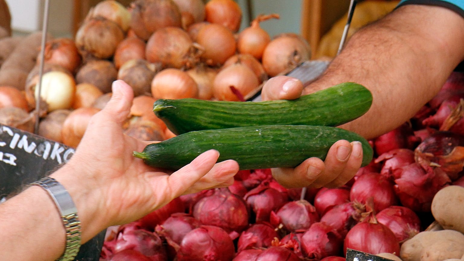 Foto de archivo de una mujer recibiendo unos pepinos en un supermercado