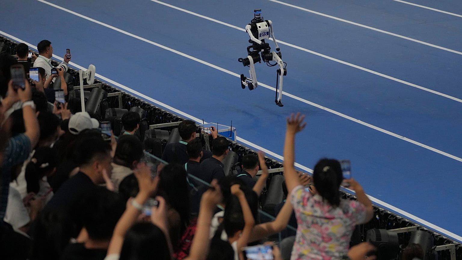 Gli spettatori fanno il tifo per un robot impegnato nei 1500 metri ai World Humanoid Robot Games a Pechino, domenica 23 agosto 2026.