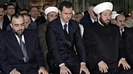 الرئيس السوري المخلوع بشار الأسد (في الوسط)، ومفتي سوريا السابق أحمد بدر الدين حسون (إلى اليمين)، يؤديان الصلاة يوم الأربعاء، 19 مارس/آذار 2008، في مسجد التقوى بوسط دمشق.